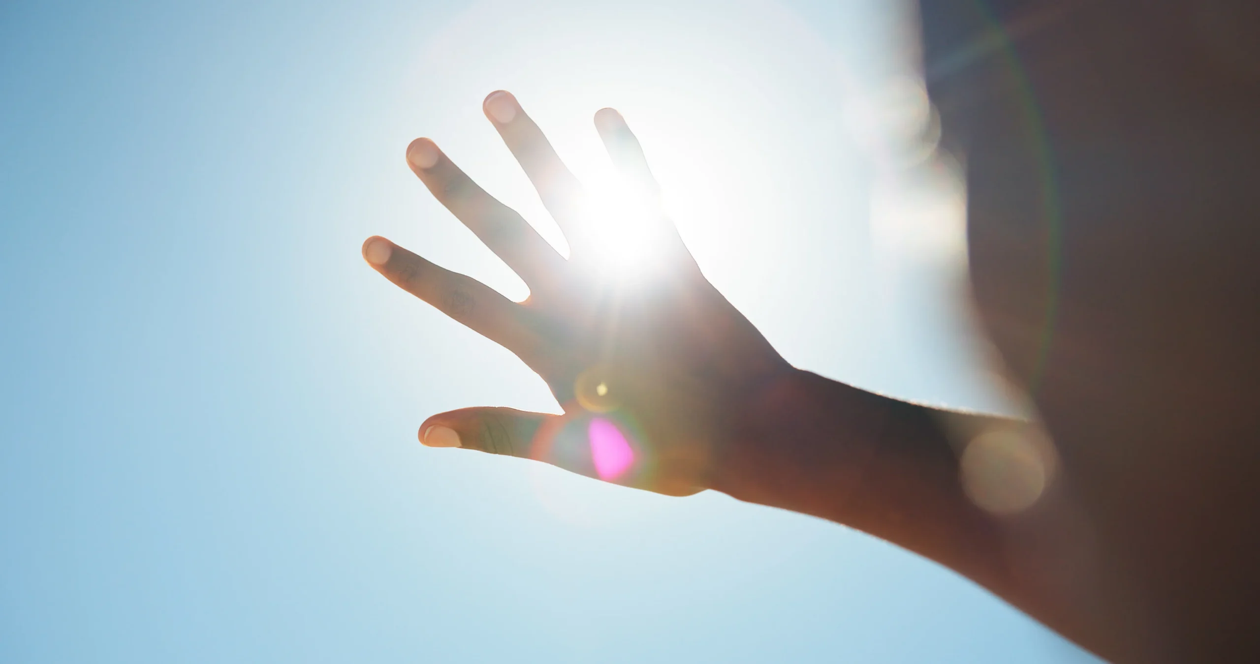person shielding their eyes by covering sunlight with hand